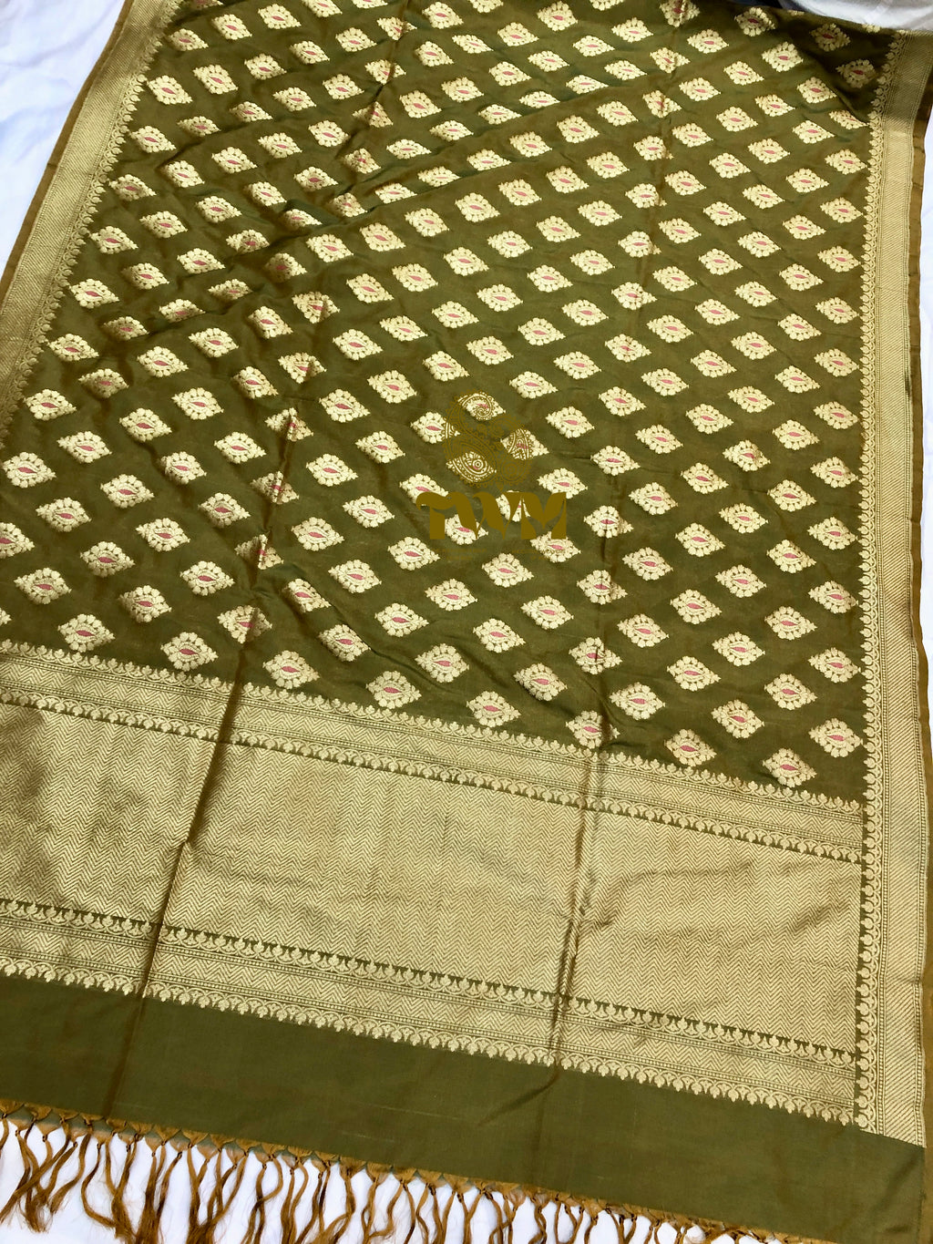 Green fabric with intricate patterns and a border on a white background