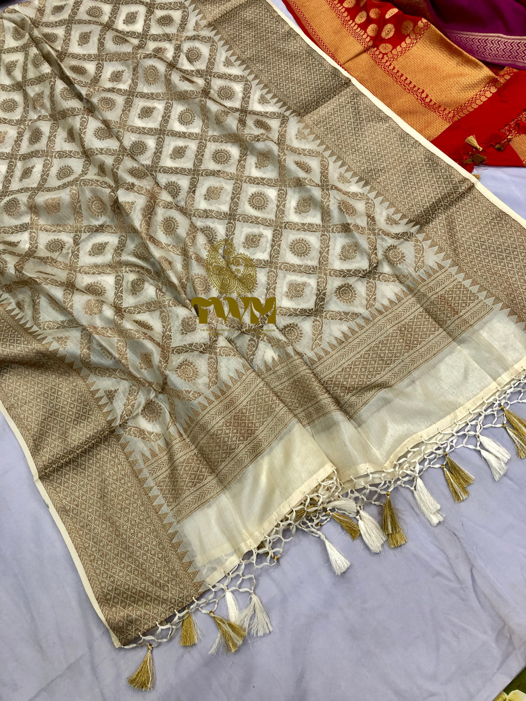 Beige and white patterned fabric with tassels on a gray surface