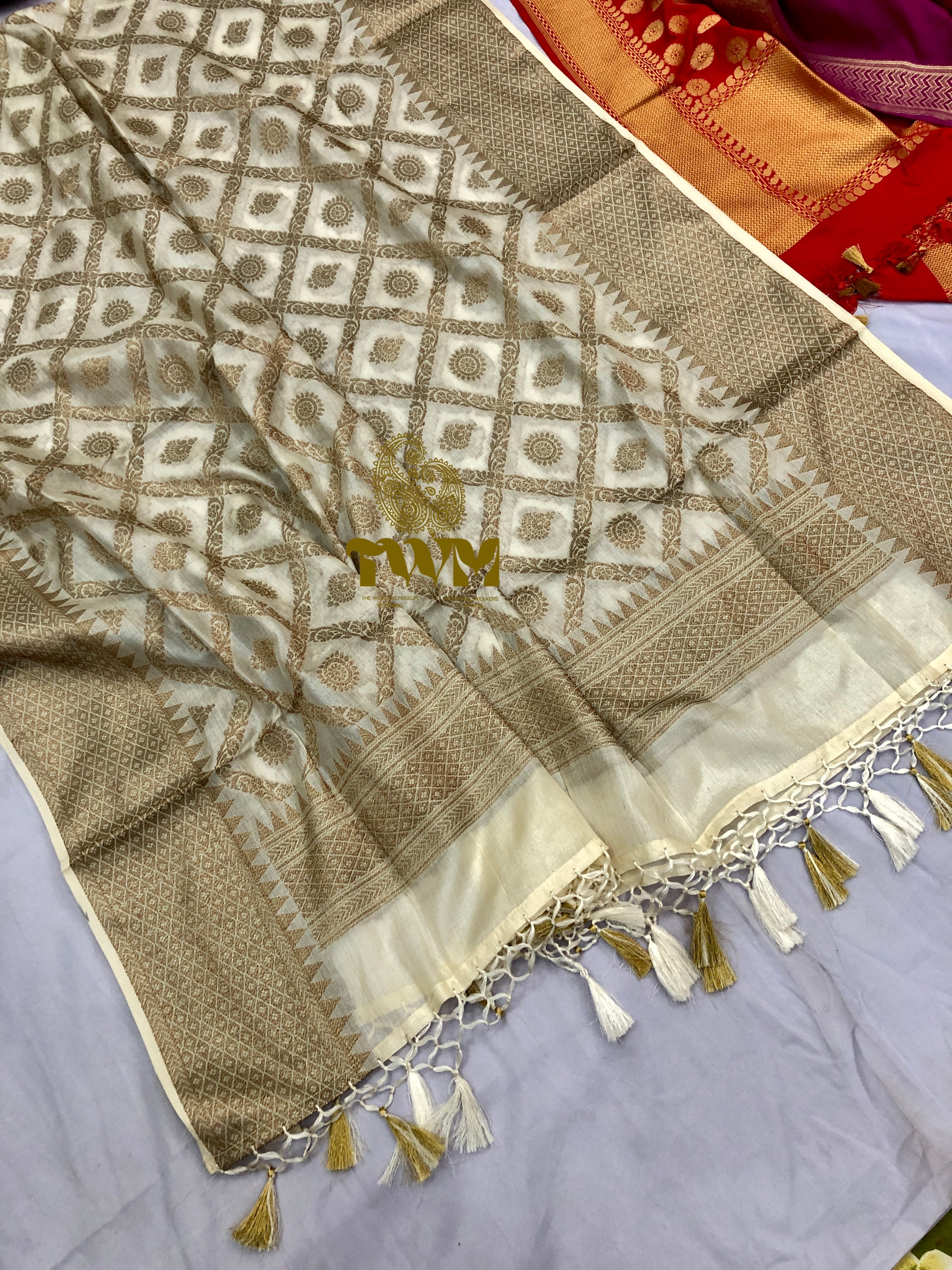 Beige and white patterned fabric with tassels on a gray surface
