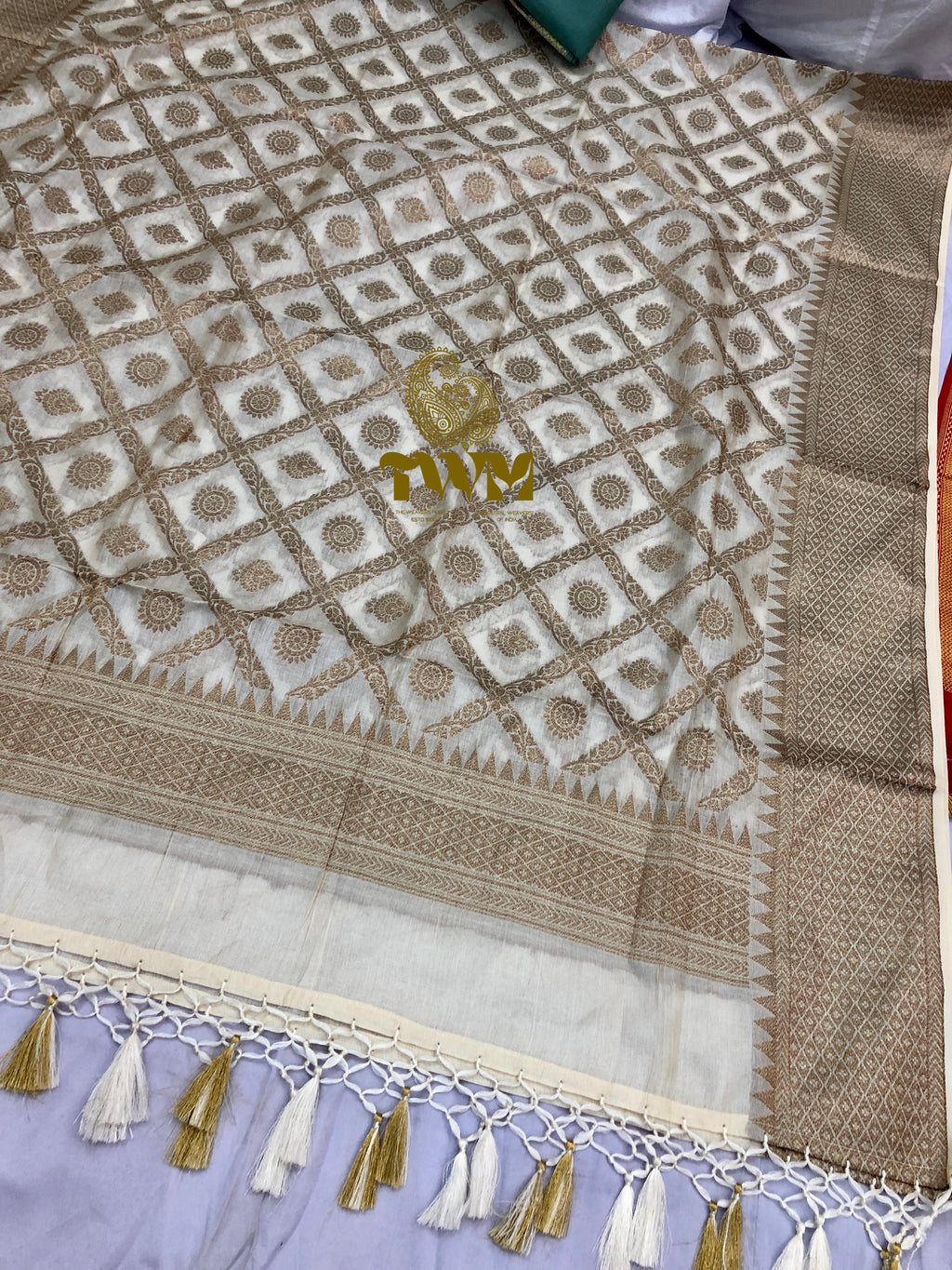 Close-up of a patterned fabric with tassels on a light background