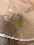 Close-up of beige fabric with a logo, possibly The Weavers Museum, on a light background.