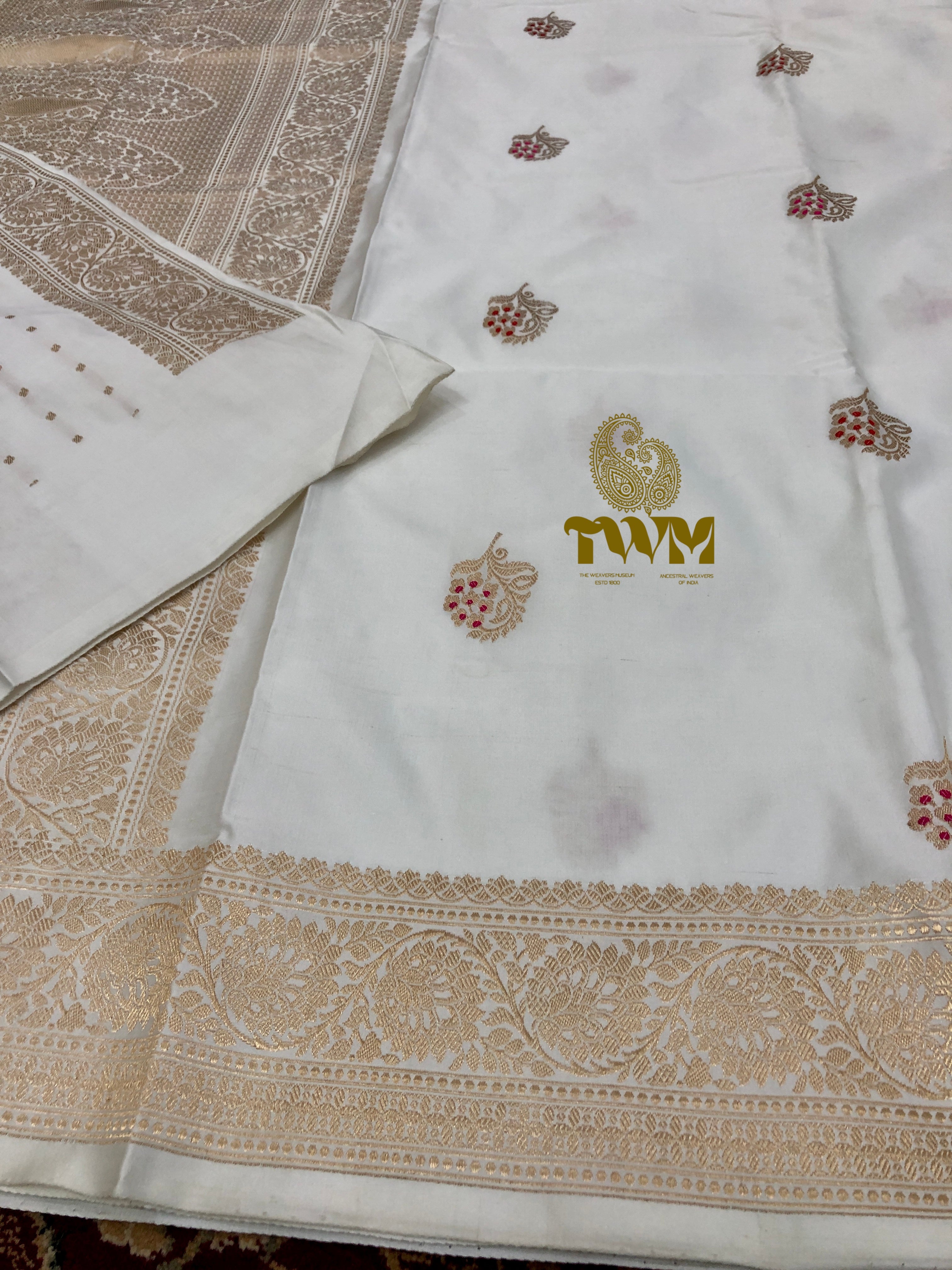 White fabric with gold embroidery and a logo on a textured surface