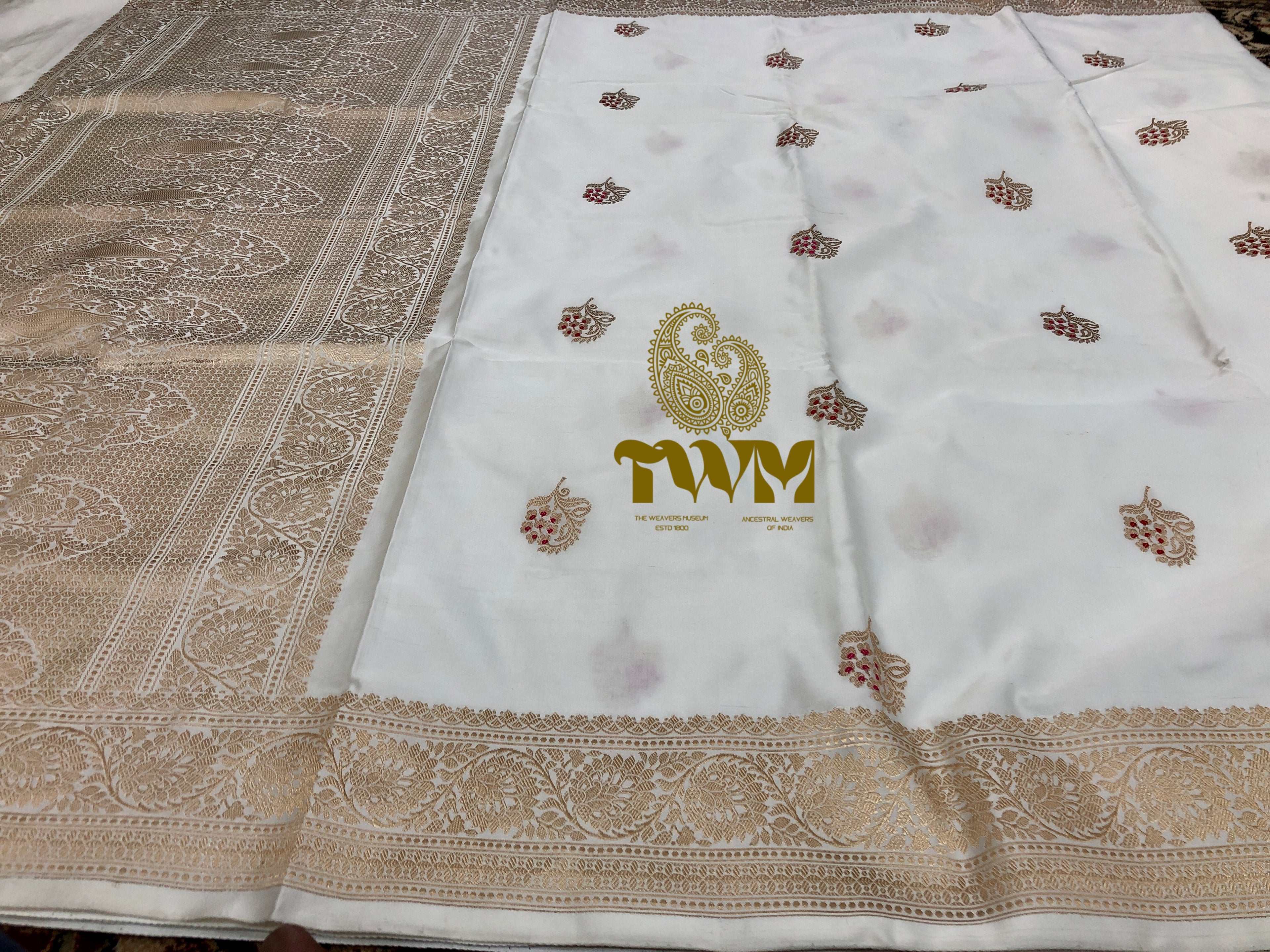 White fabric with gold embroidery and a logo on a textured surface