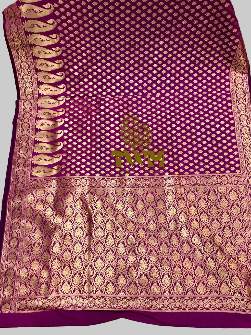 Purple fabric with intricate gold patterns on a green leafy background