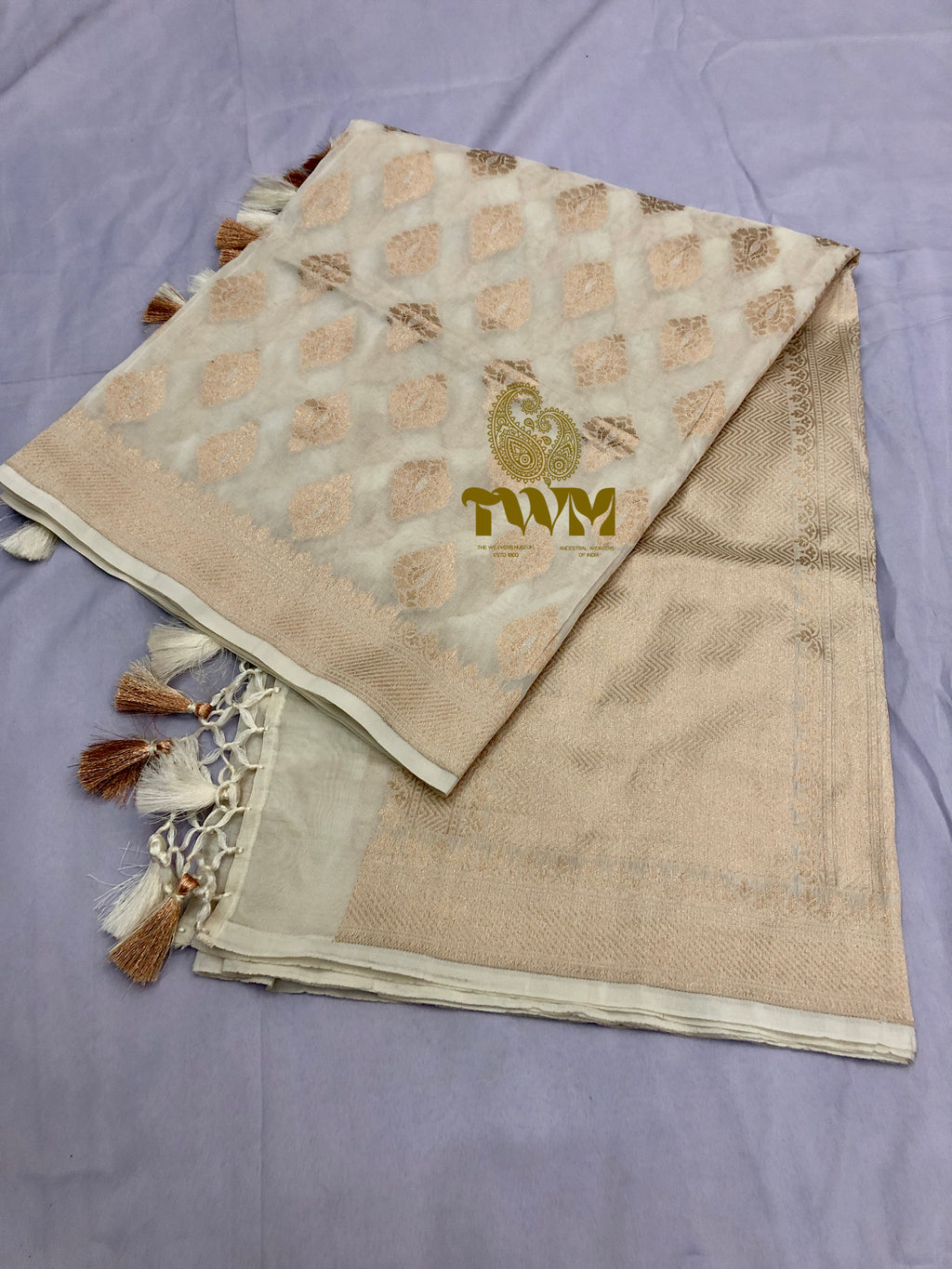 Beige fabric with tassels and a logo on a purple surface