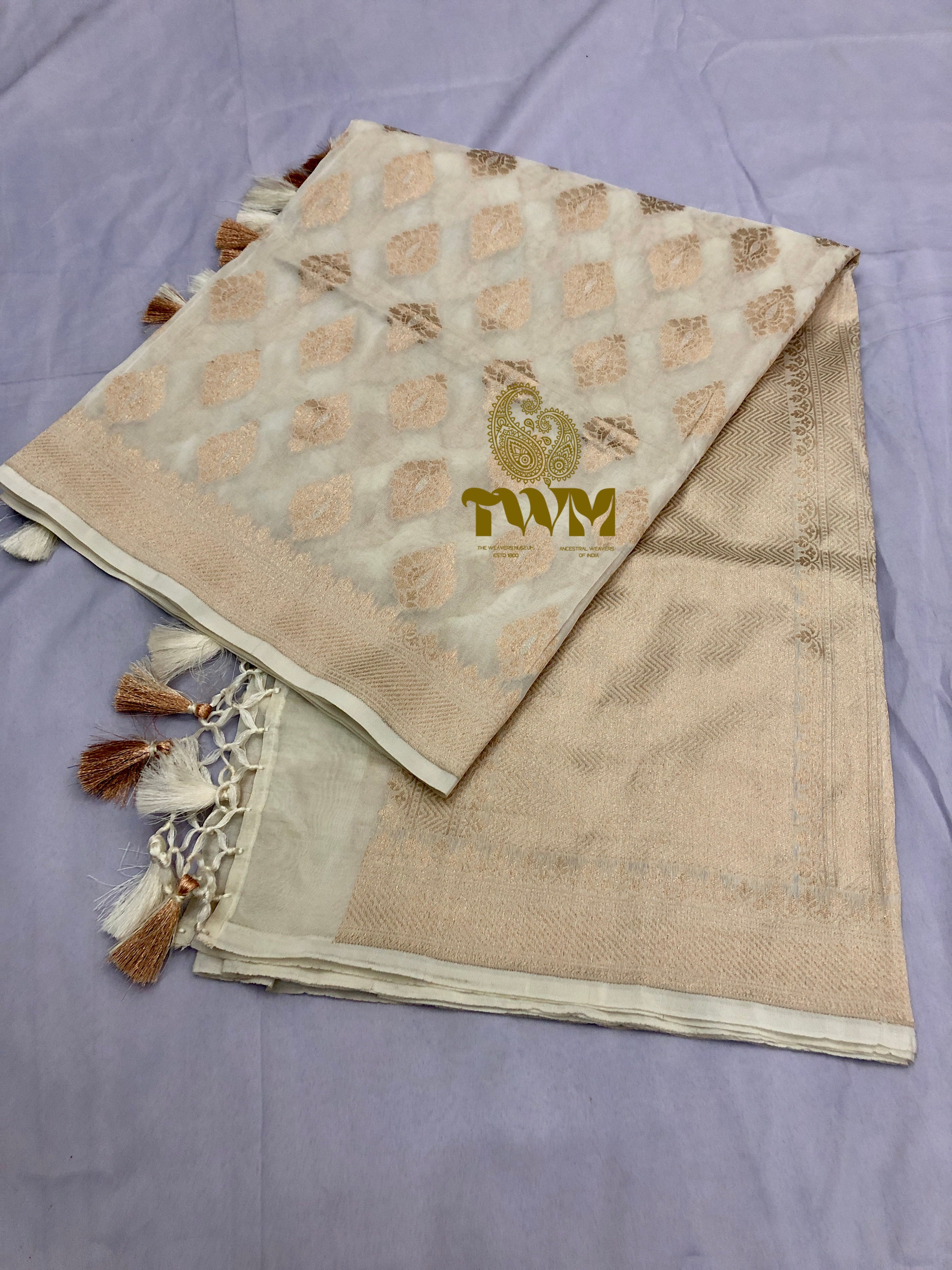 Beige fabric with tassels and a logo on a purple surface