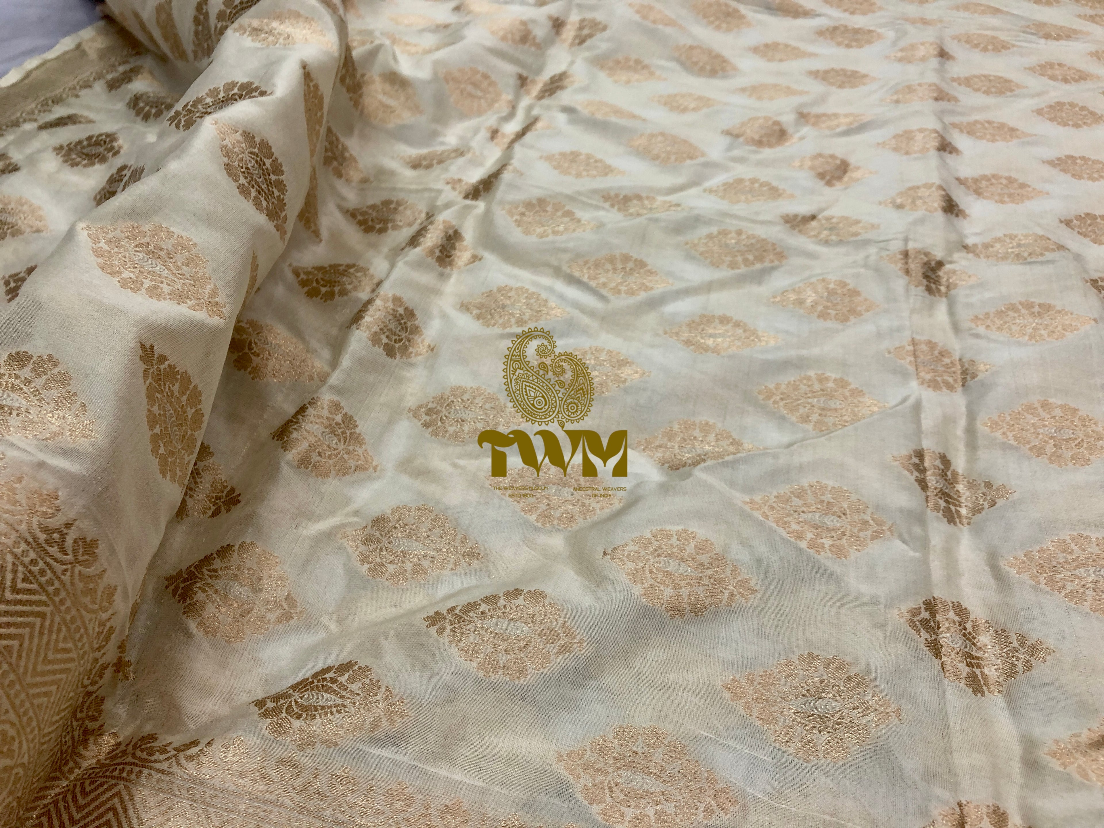 Textured fabric with gold patterns and a logo on a light background