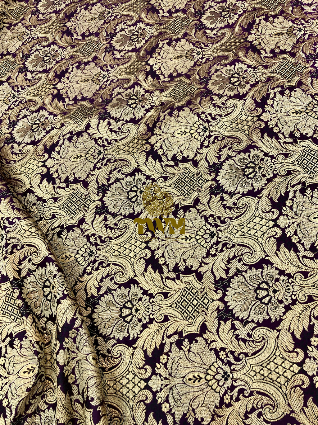 Decorative fabric with intricate paisley pattern in gold on a dark background