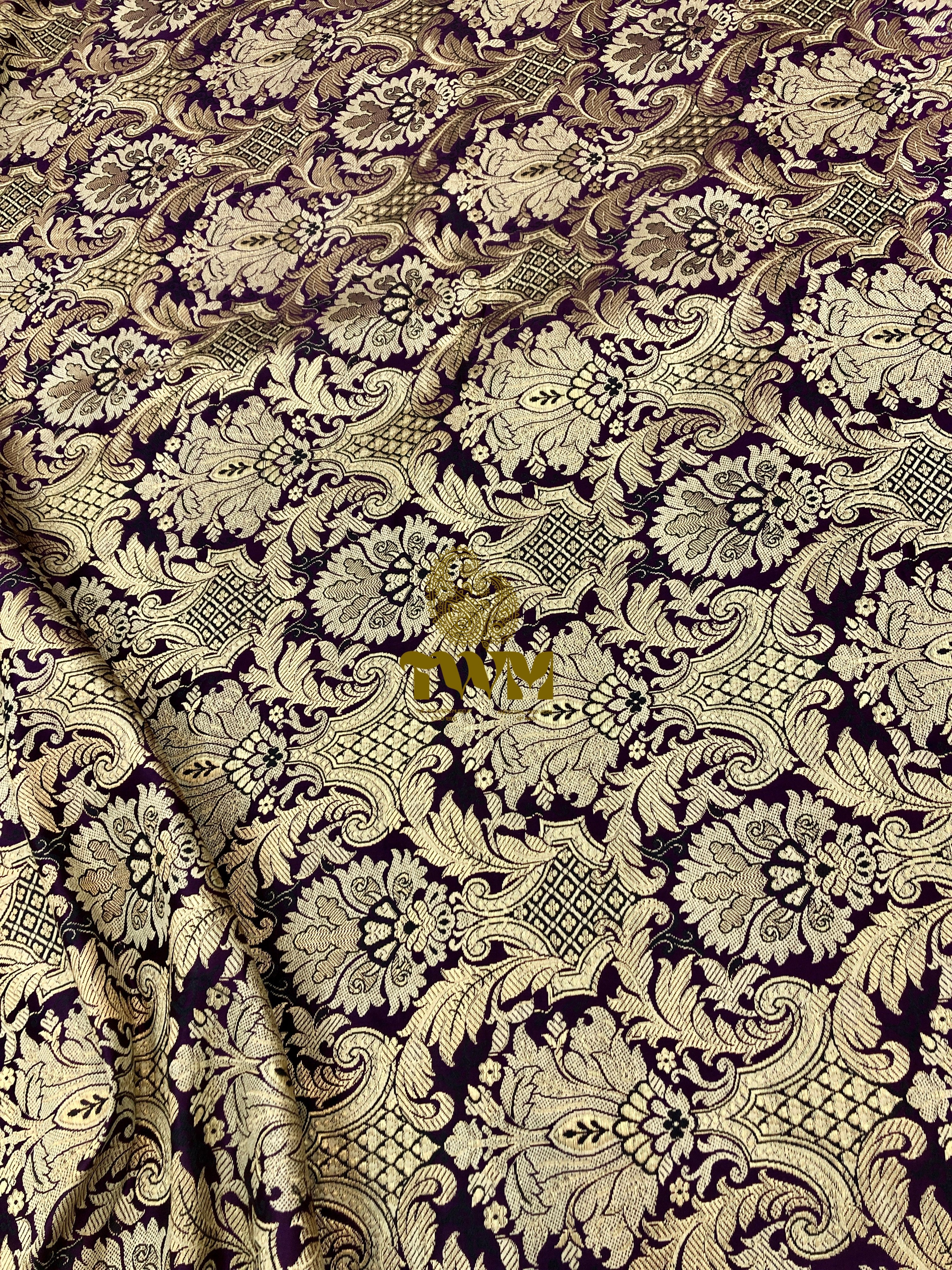 Decorative fabric with intricate paisley pattern in gold on a dark background