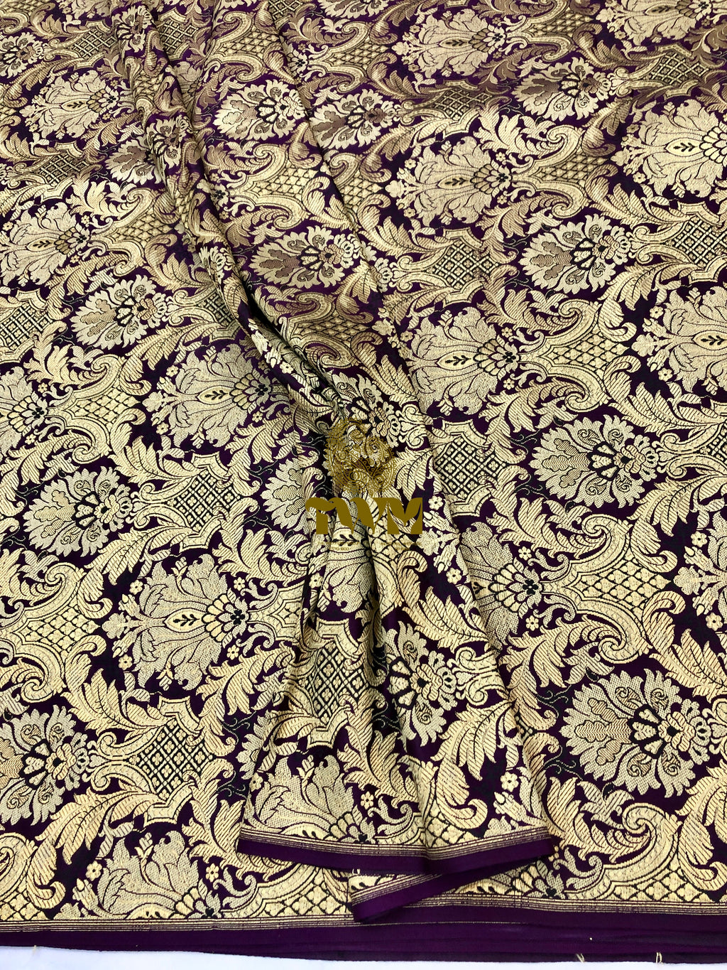 Decorative fabric with intricate gold and black pattern on a dark background