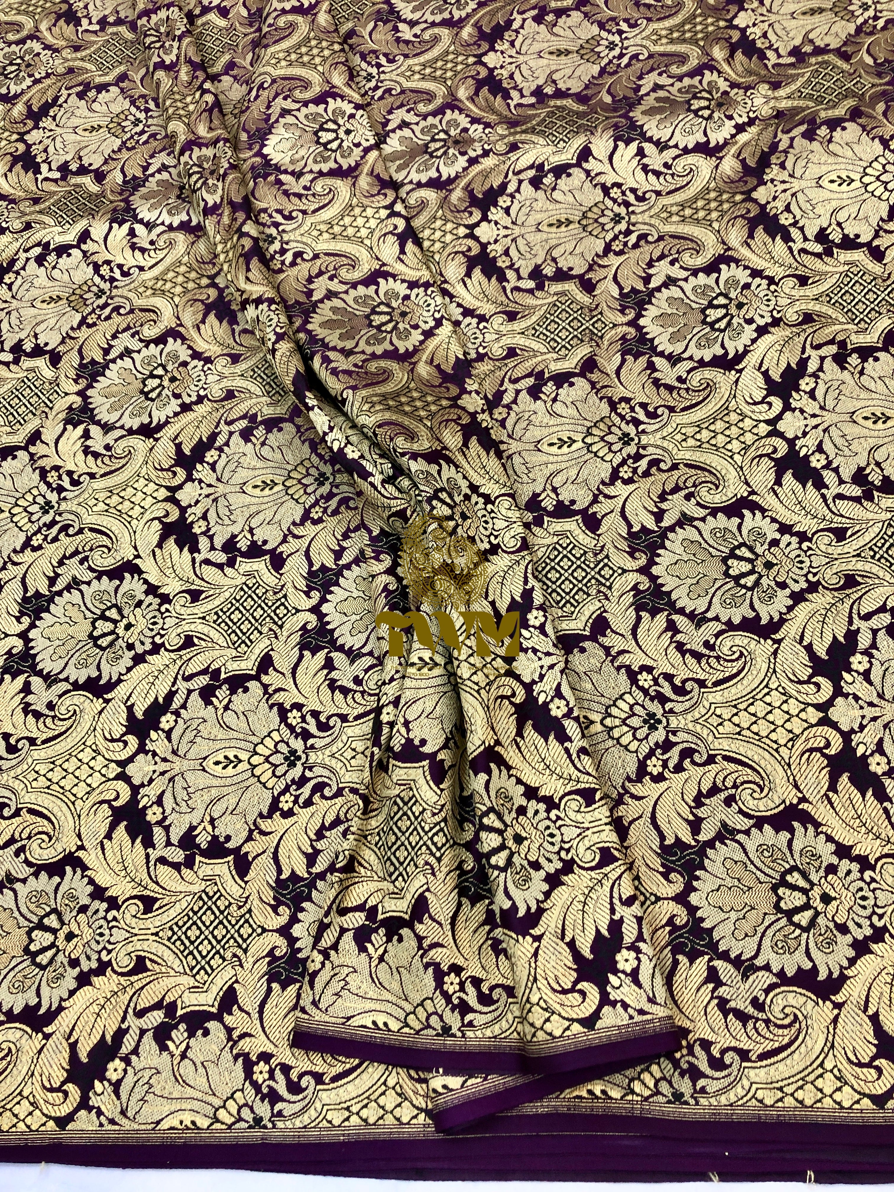 Decorative fabric with intricate gold and black pattern on a dark background