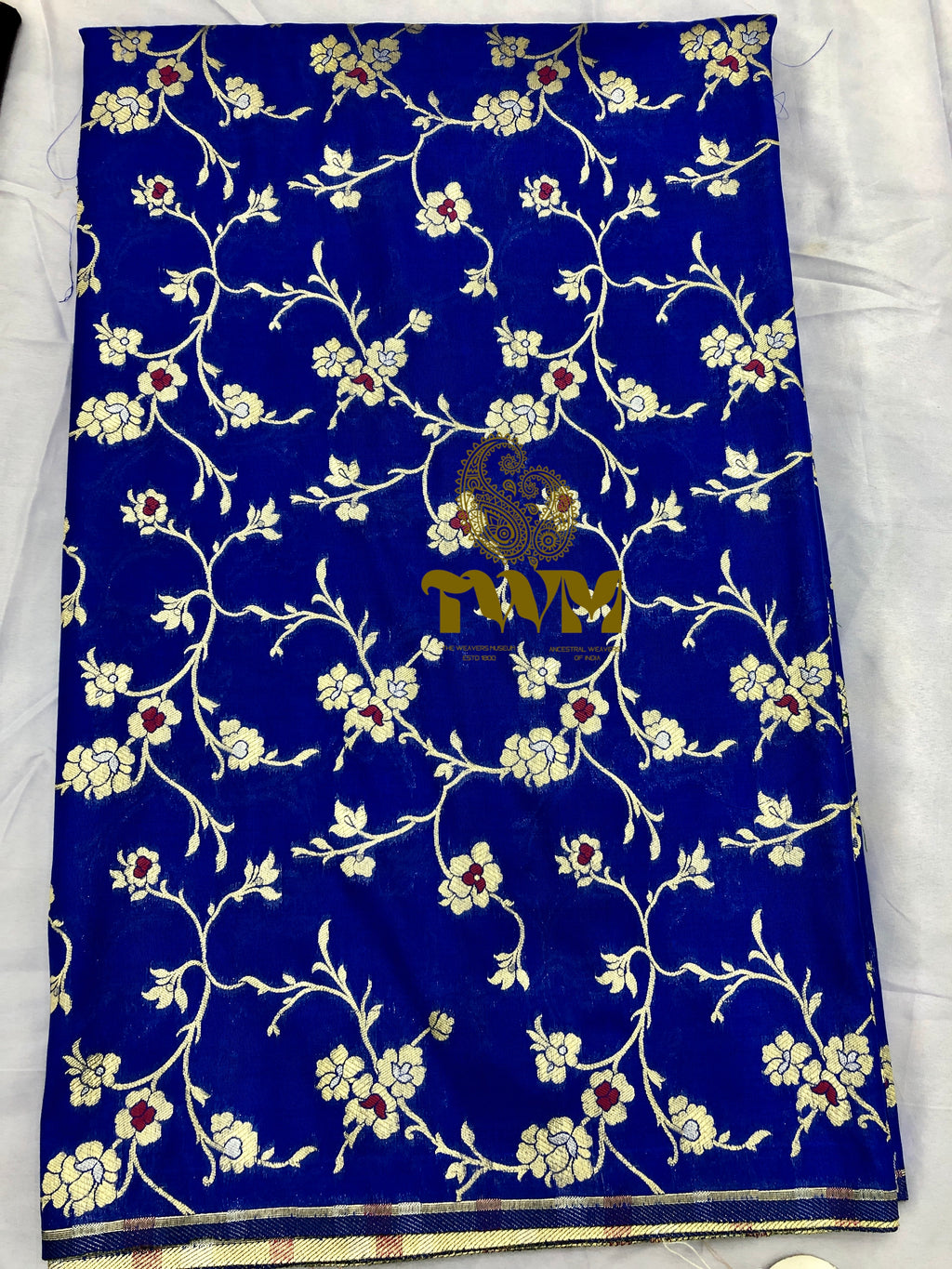 Blue fabric with floral patterns and a brand name on a white background