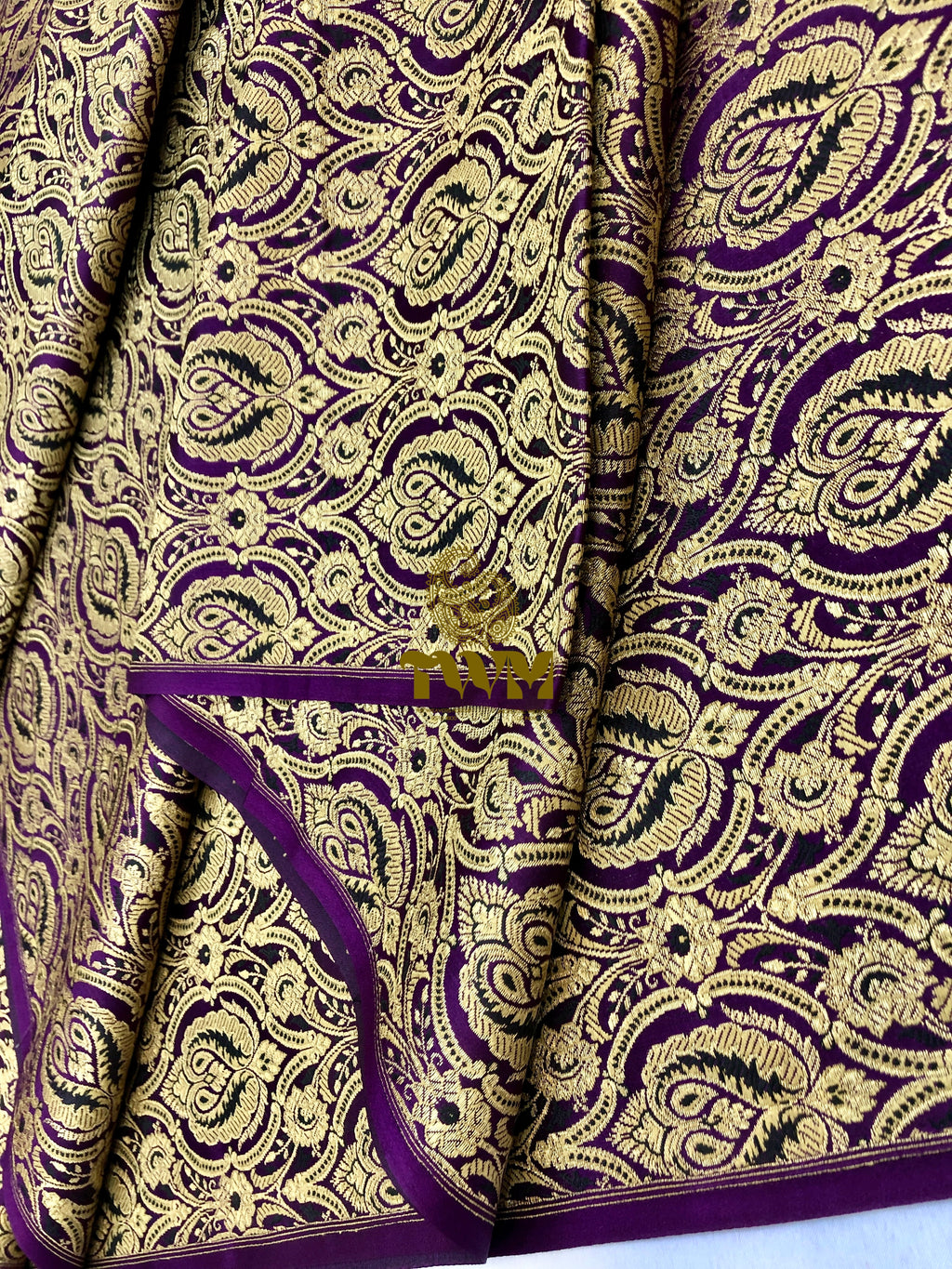Patterned fabric with gold and purple design on a white background