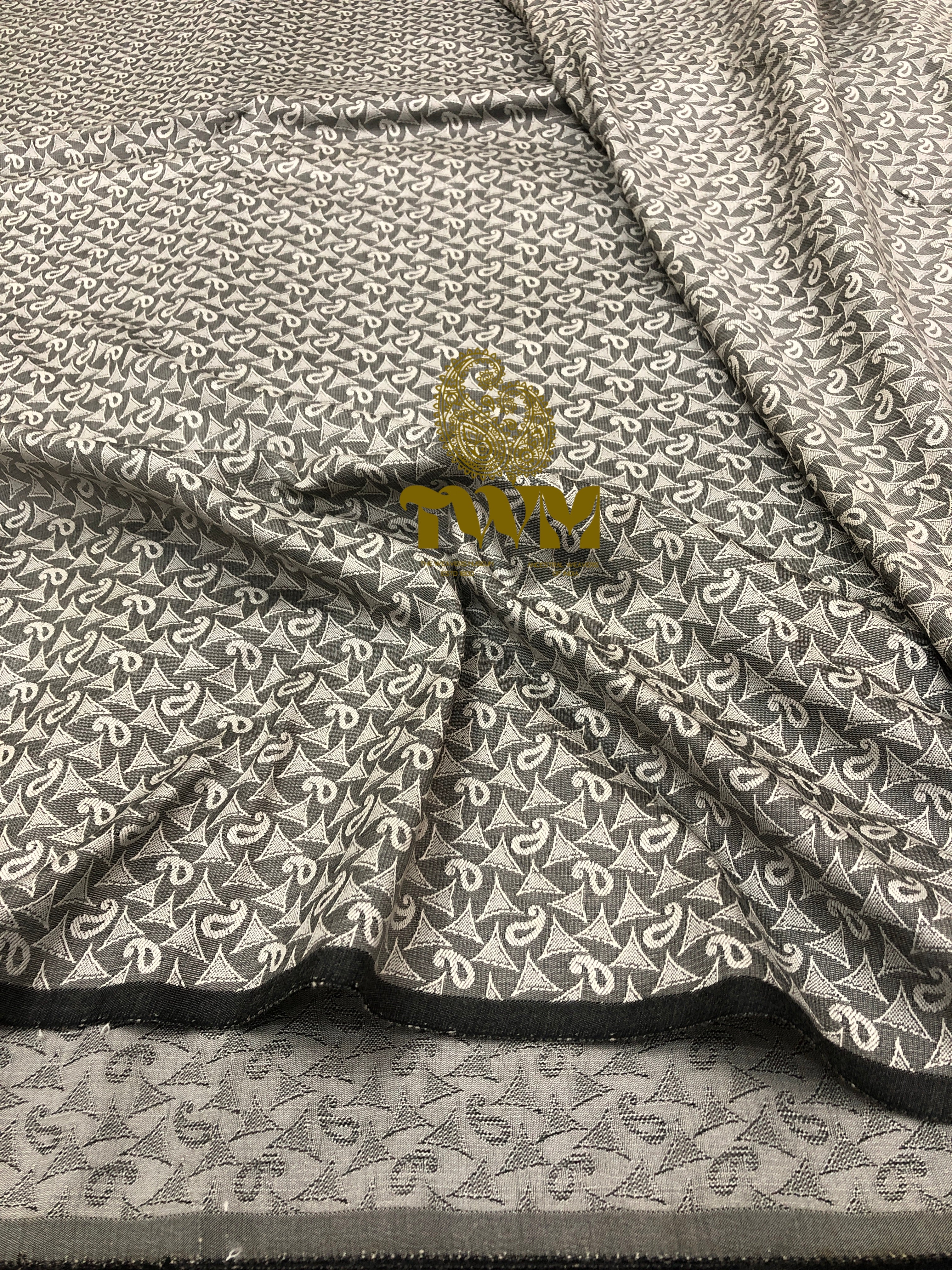Textile with a geometric pattern and a gold emblem on a gray background
