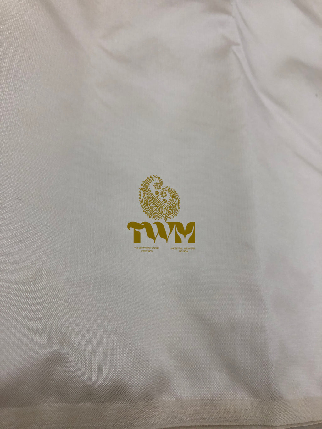 White shirt with gold logo and text on a plain background