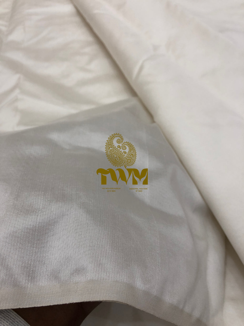 Close-up of a white fabric with a gold logo on a gray background
