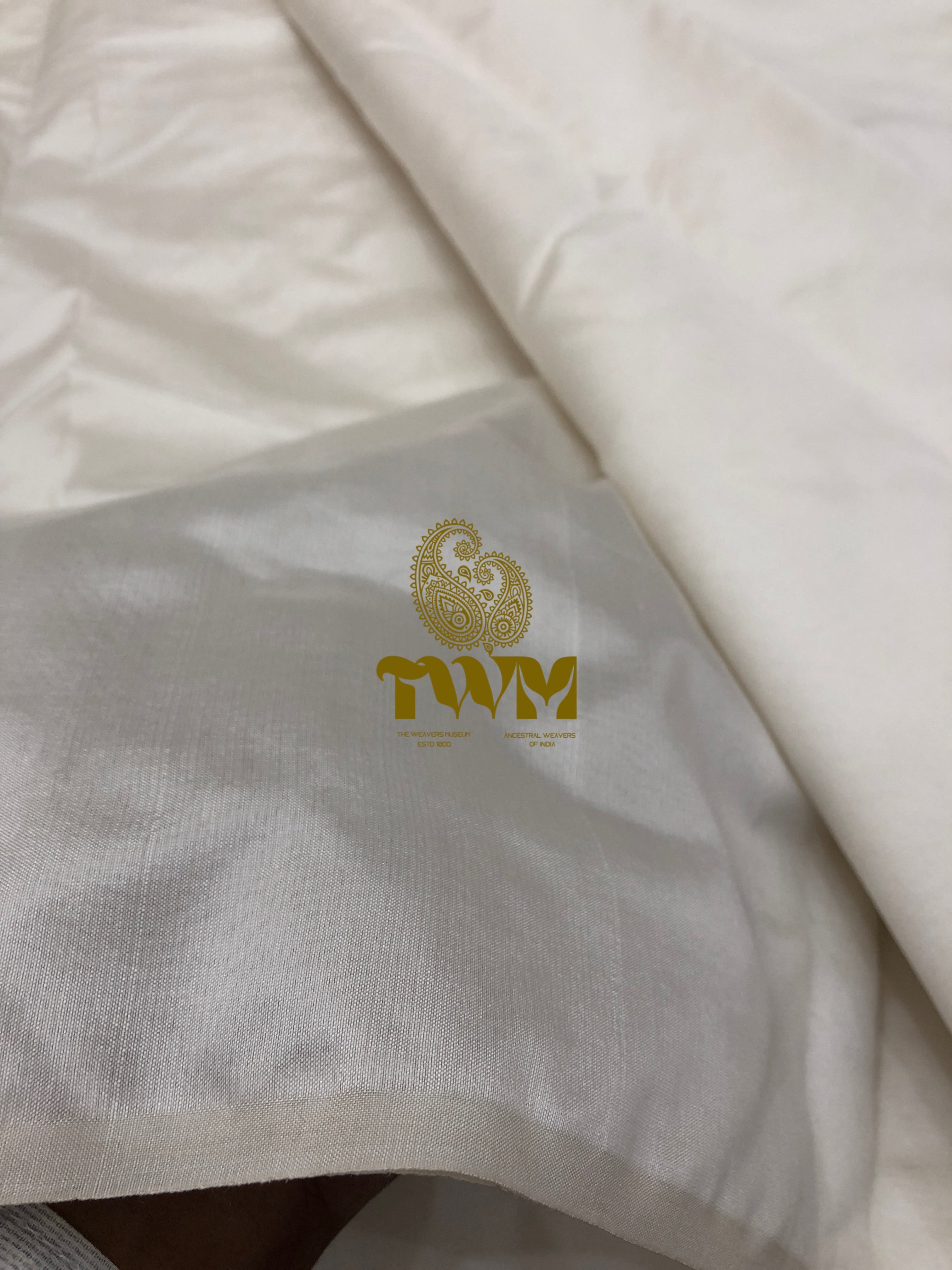 Close-up of a white fabric with a gold logo on a gray background