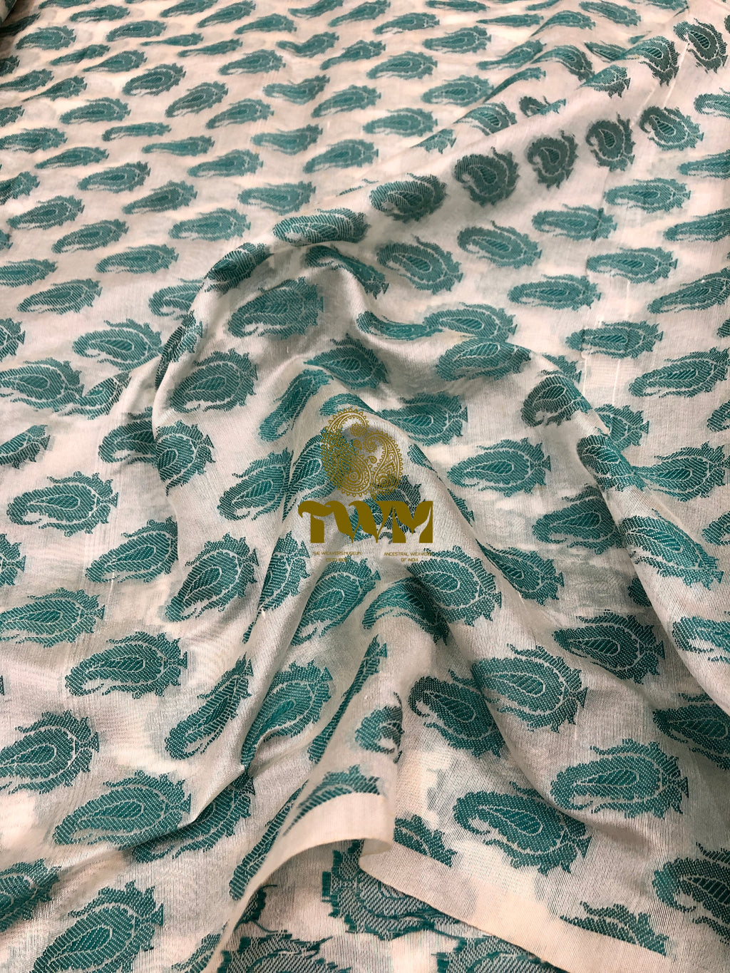 Fabric with green paisley pattern and a visible brand label.