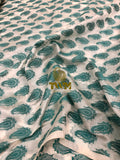 Fabric with green paisley pattern and a visible brand label.