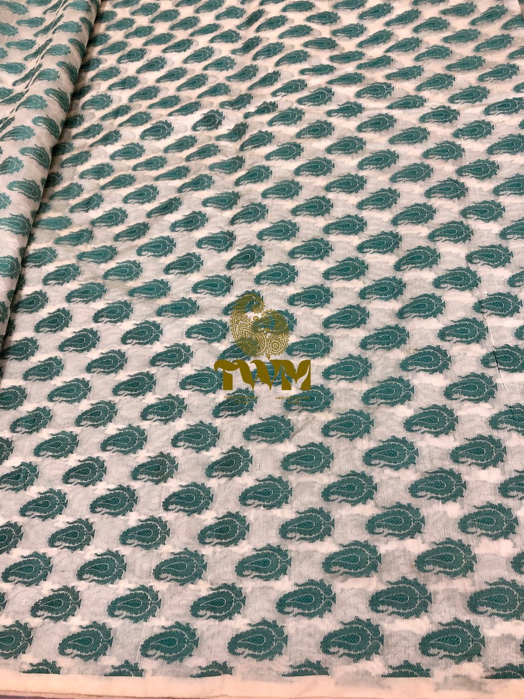 Textile with green leaf pattern and 'TWM' branding on a beige background