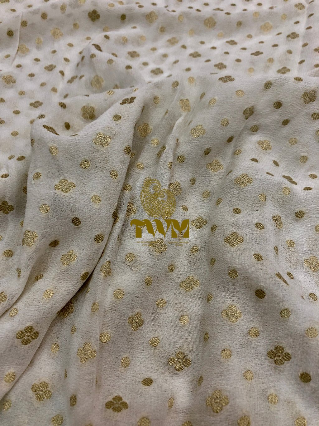 Textured fabric with gold floral patterns and a visible brand logo.
