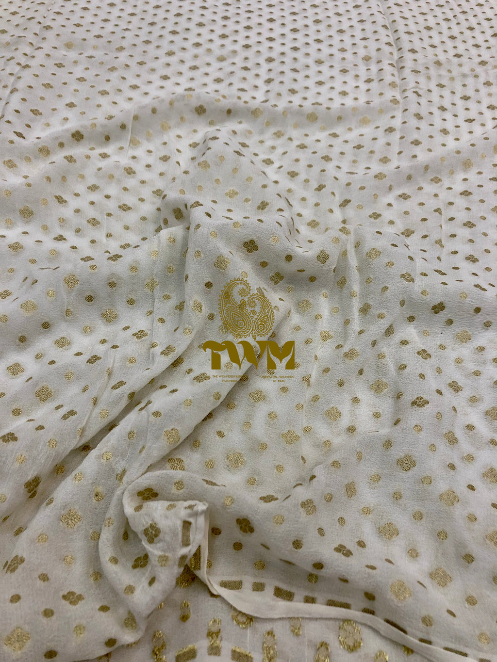 White fabric with gold patterns and a logo, likely a brand emblem.