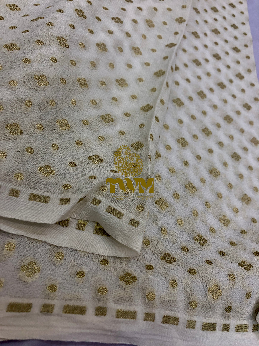 White fabric with gold floral patterns on a light purple background