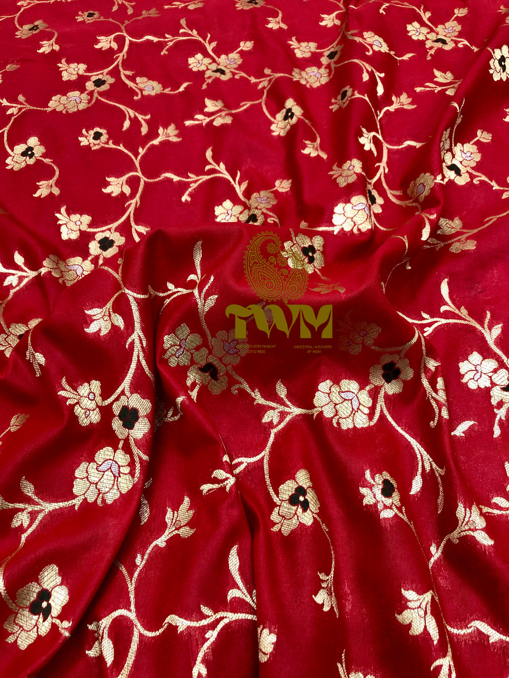 Red fabric with floral patterns and a visible brand logo in the center.
