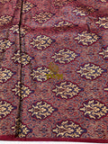 Close-up of a patterned fabric with intricate designs on a red background