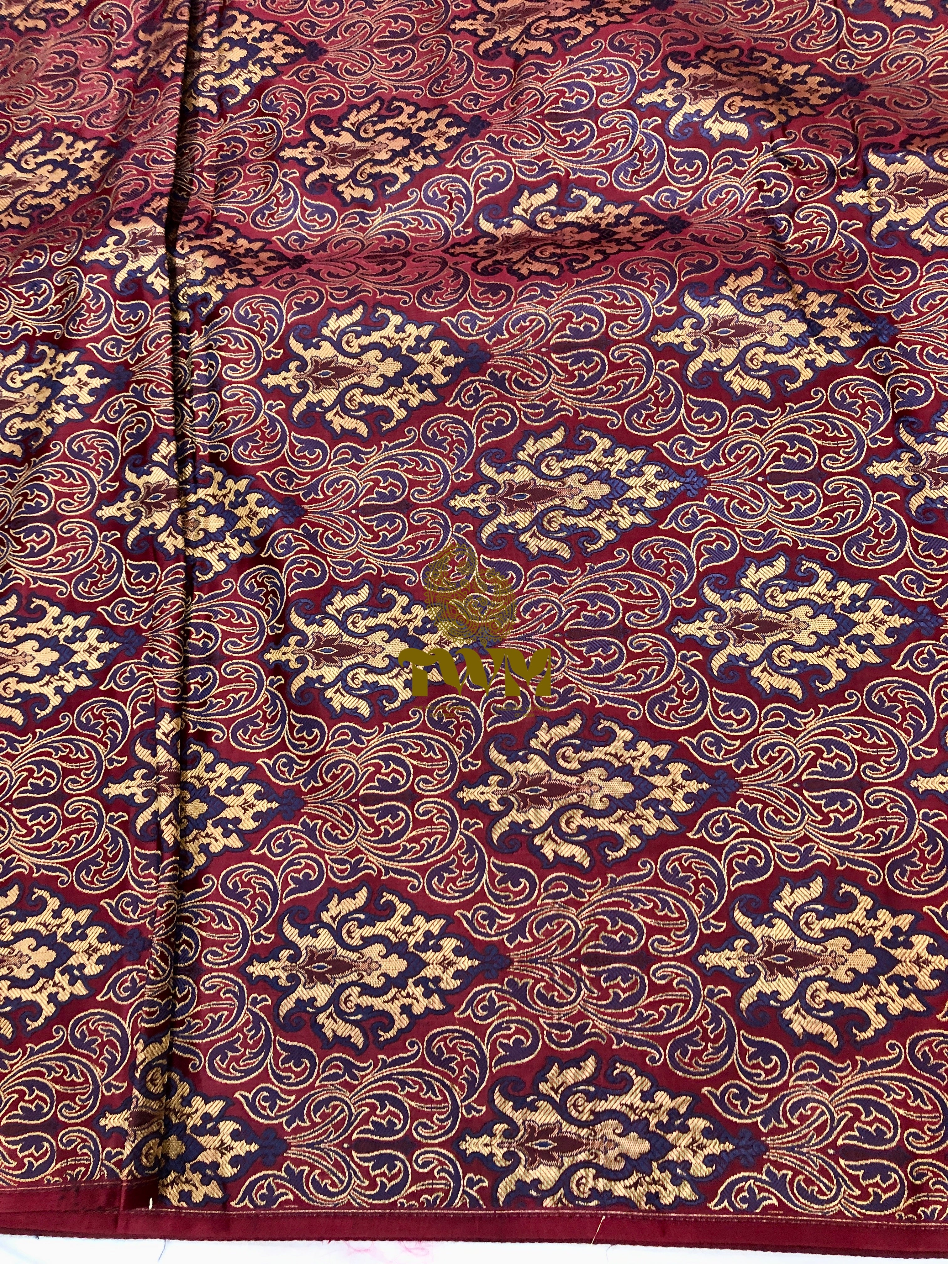 Close-up of a patterned fabric with intricate designs on a red background