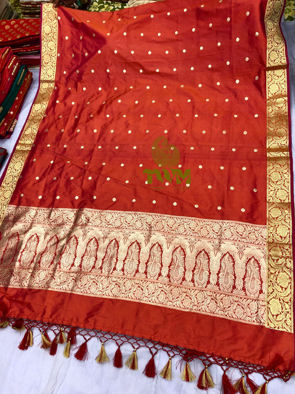Orange dupatta with gold patterns and a logo on a white background