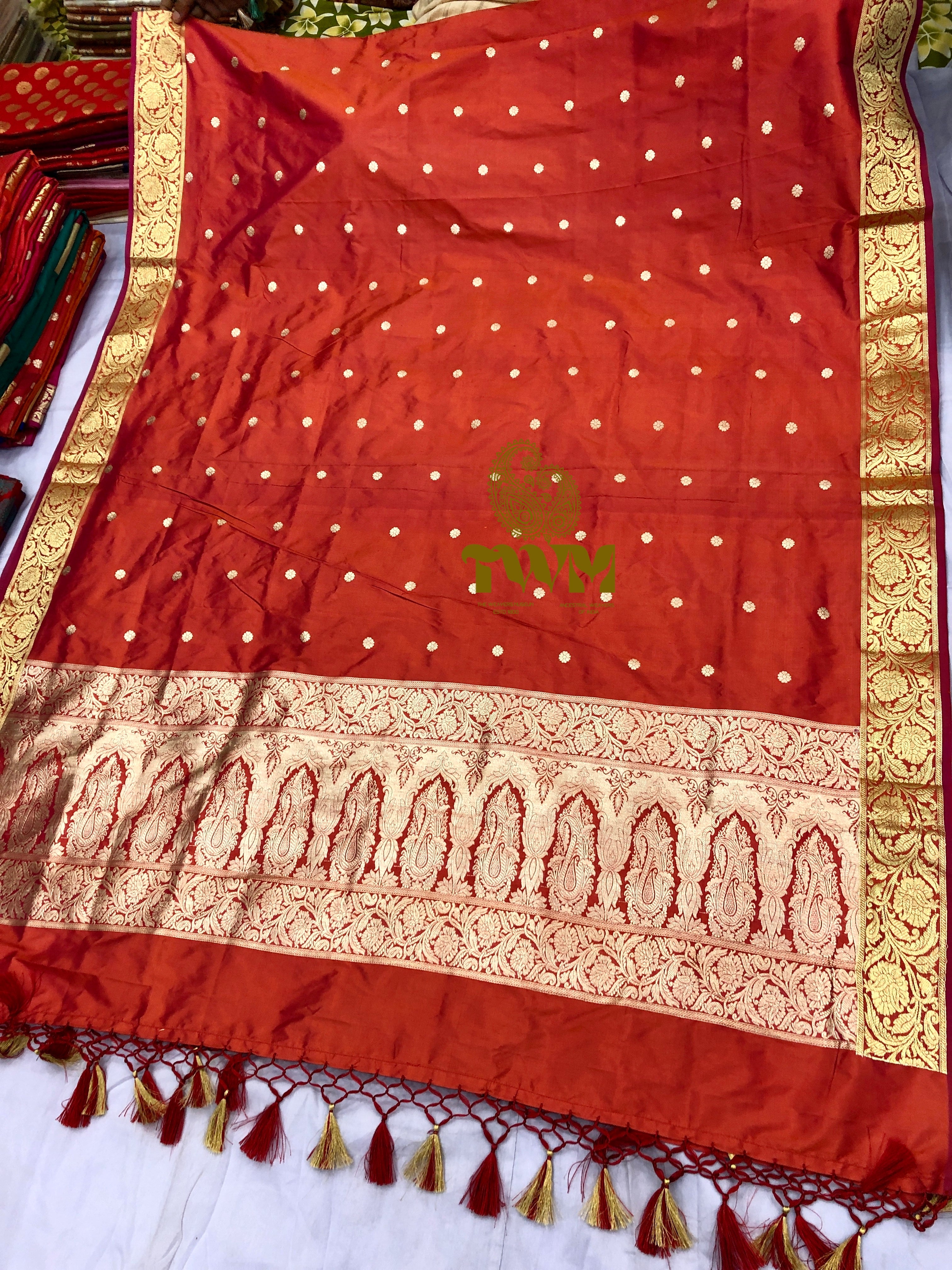 Orange dupatta with gold patterns and a logo on a white background