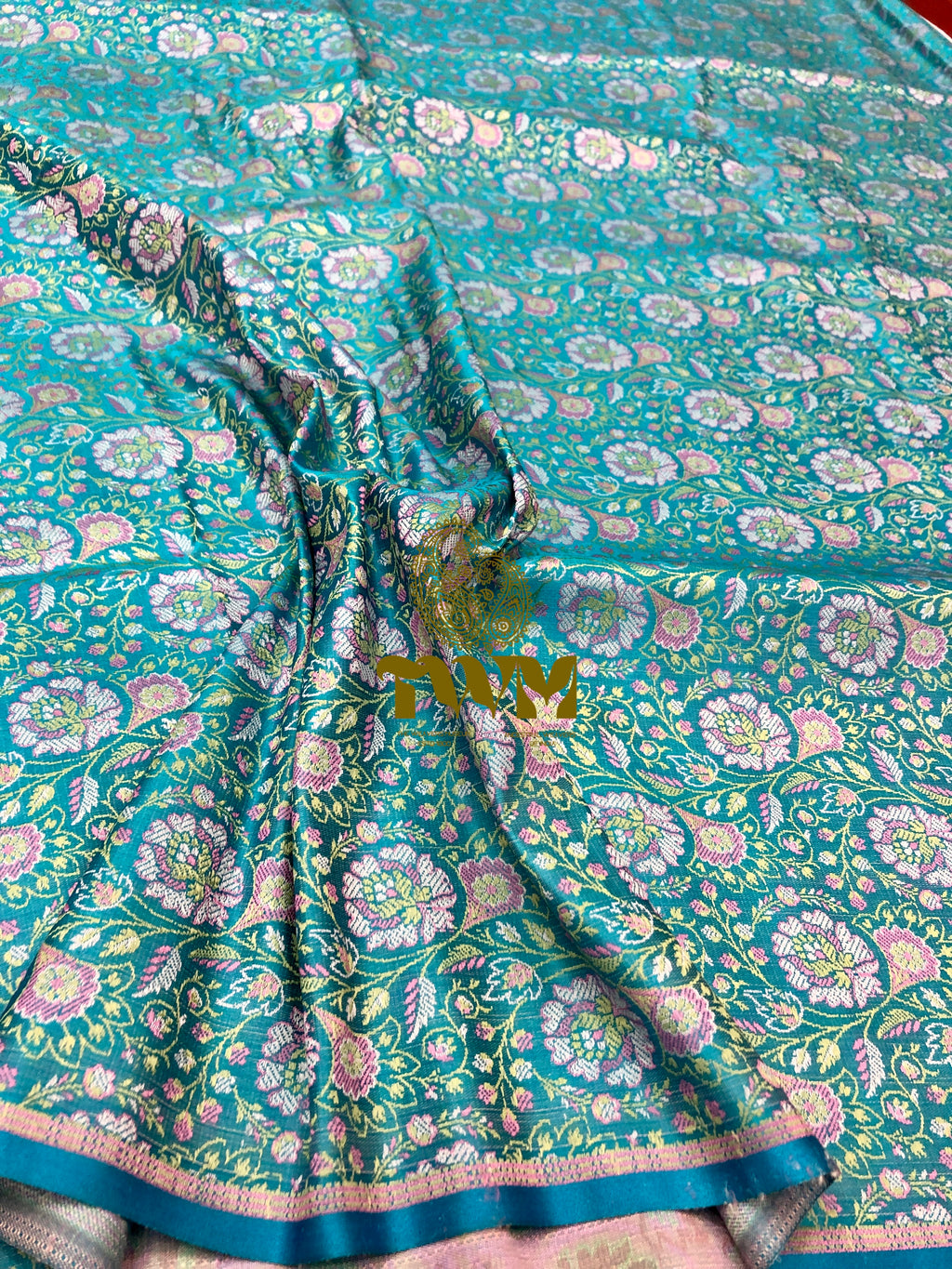 Teal saree with floral patterns and a gold border